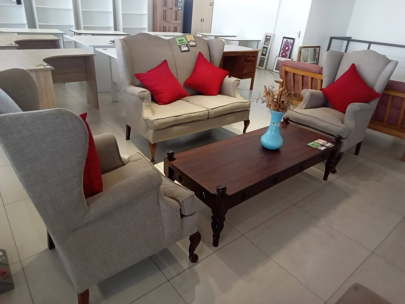 Three-piece linen wingback lounge set with red accent cushions and mahogany coffee table